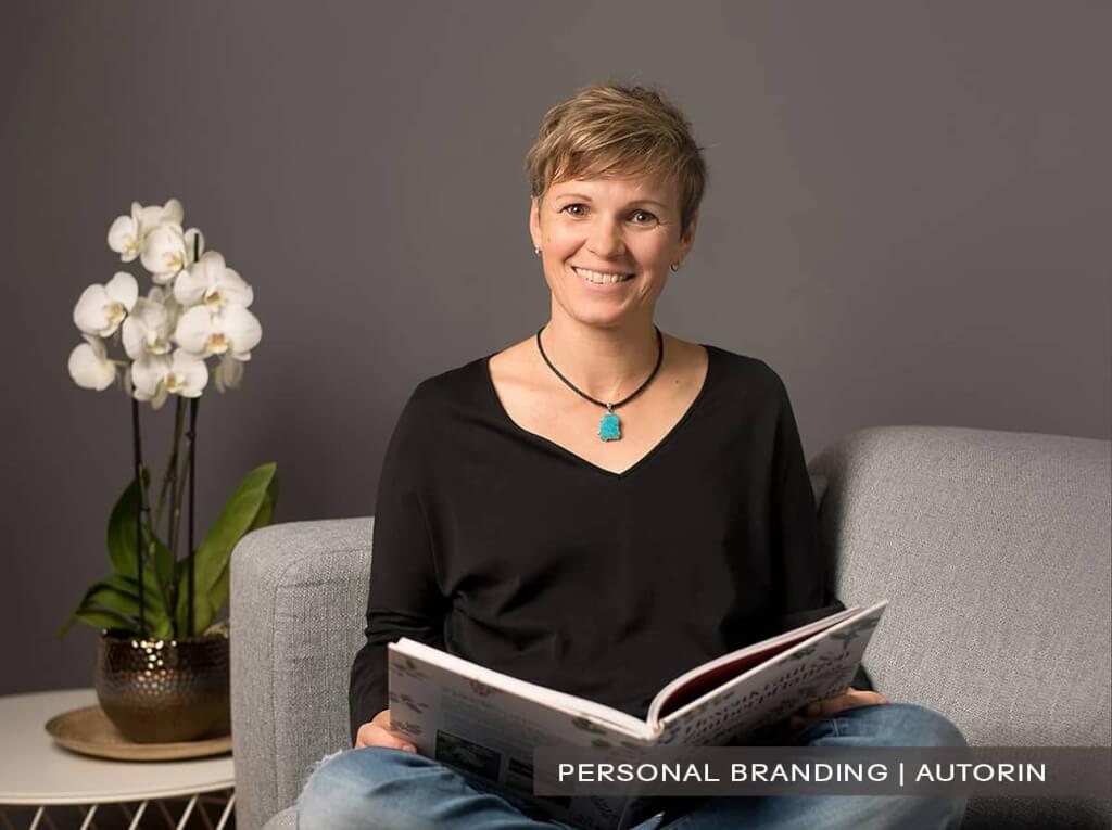 Professionelles Personal-Branding-Portrait einer Autorin auf einem Sofa mit einem geöffneten Buch in den Händen, sympathisch und modern fotografiert in Wuppertal von Josephine Scharrer