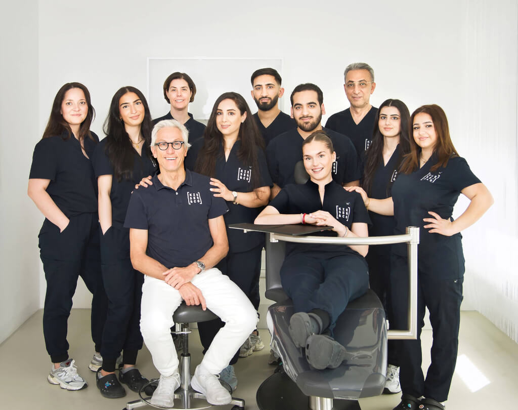 Dynamisches und helles Gruppenbild eines elfköpfigen Teams rund um einen Behandlungsstuhl, modern und professionell im B2B-Business-Shooting von der Fotografin inszeniert