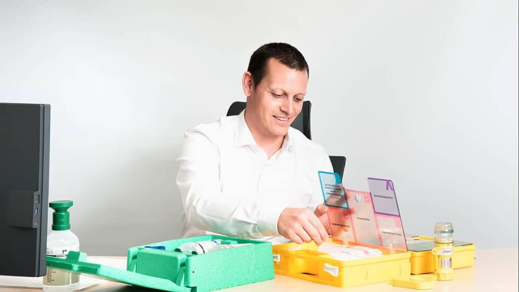 Authentisches Businessportrait eines Mitarbeiters im weißen Hemd, der aktiv mit Arbeitsgeräten an seinem sauberen, modern gestalteten Arbeitsplatz agiert.
