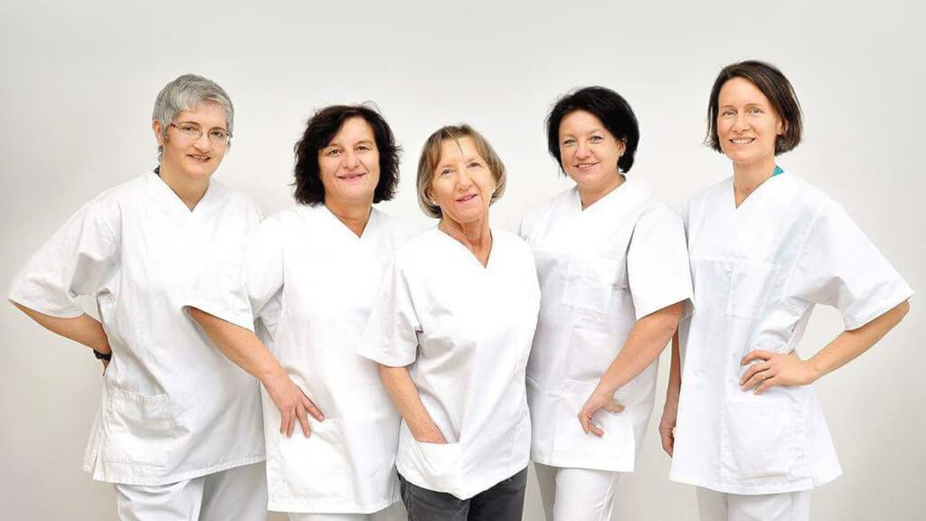 Sympathisches Gruppenbild eines fünfköpfigen medizinischen Pflegeteams und Hebammenteams, hell und einheitlich direkt im Krankenhaus fotografiert