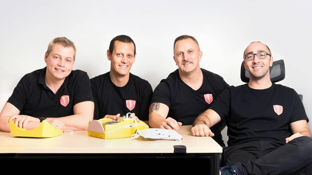 Sympathisches und nahbares Gruppenbild von vier Mitarbeitern an einem Besprechungstisch bei einem professionellen Firmen-Shooting vor Ort